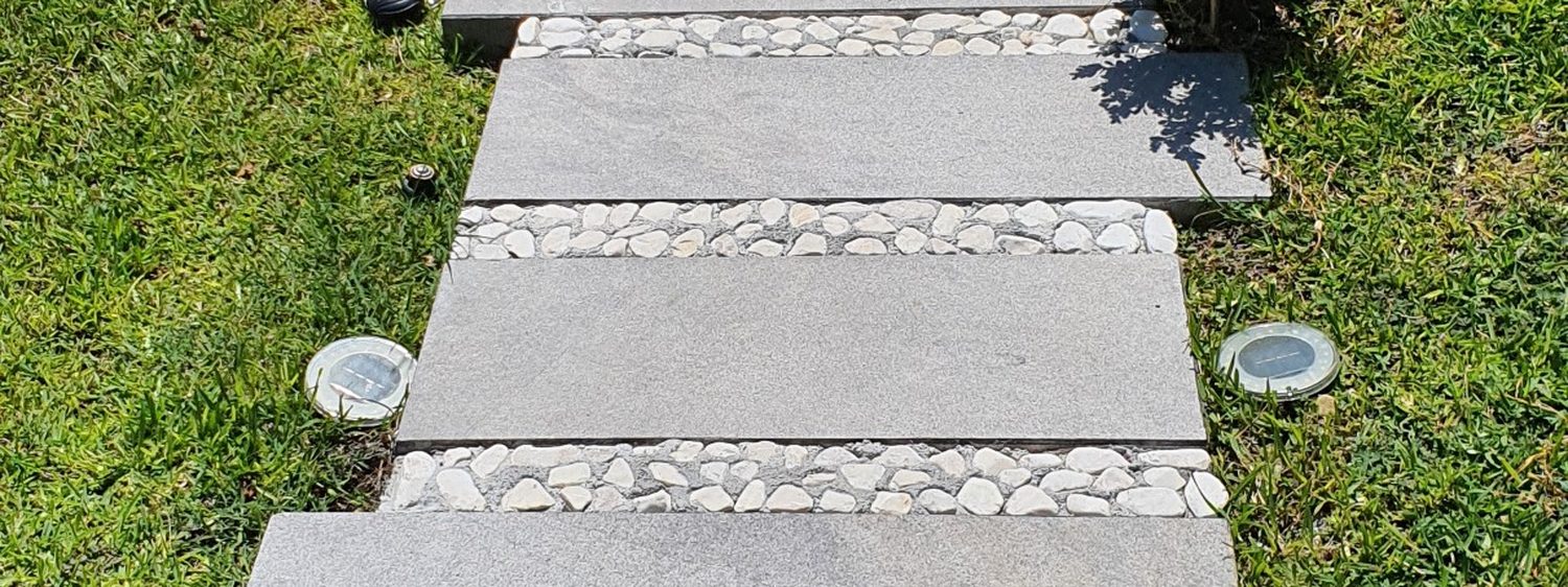 Andador de piedra sobre jardín con iluminación